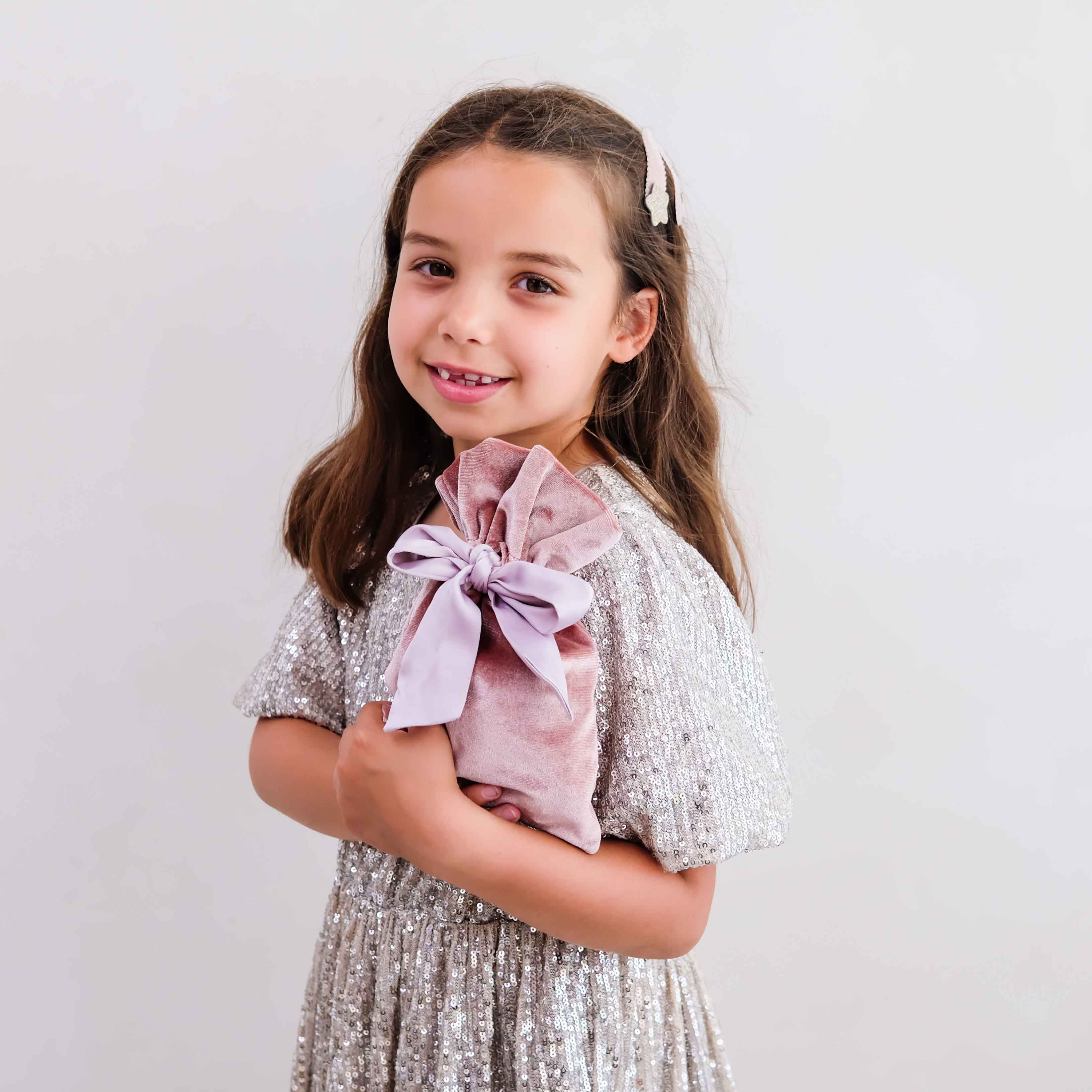 Child holding Mimi & Lula pink gifting pouch