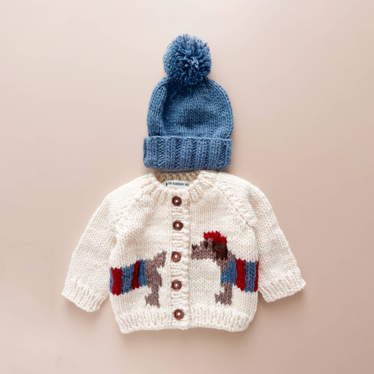 The Blueberry Hill Dachshund Cardigan styled with a blue pom-pom hat