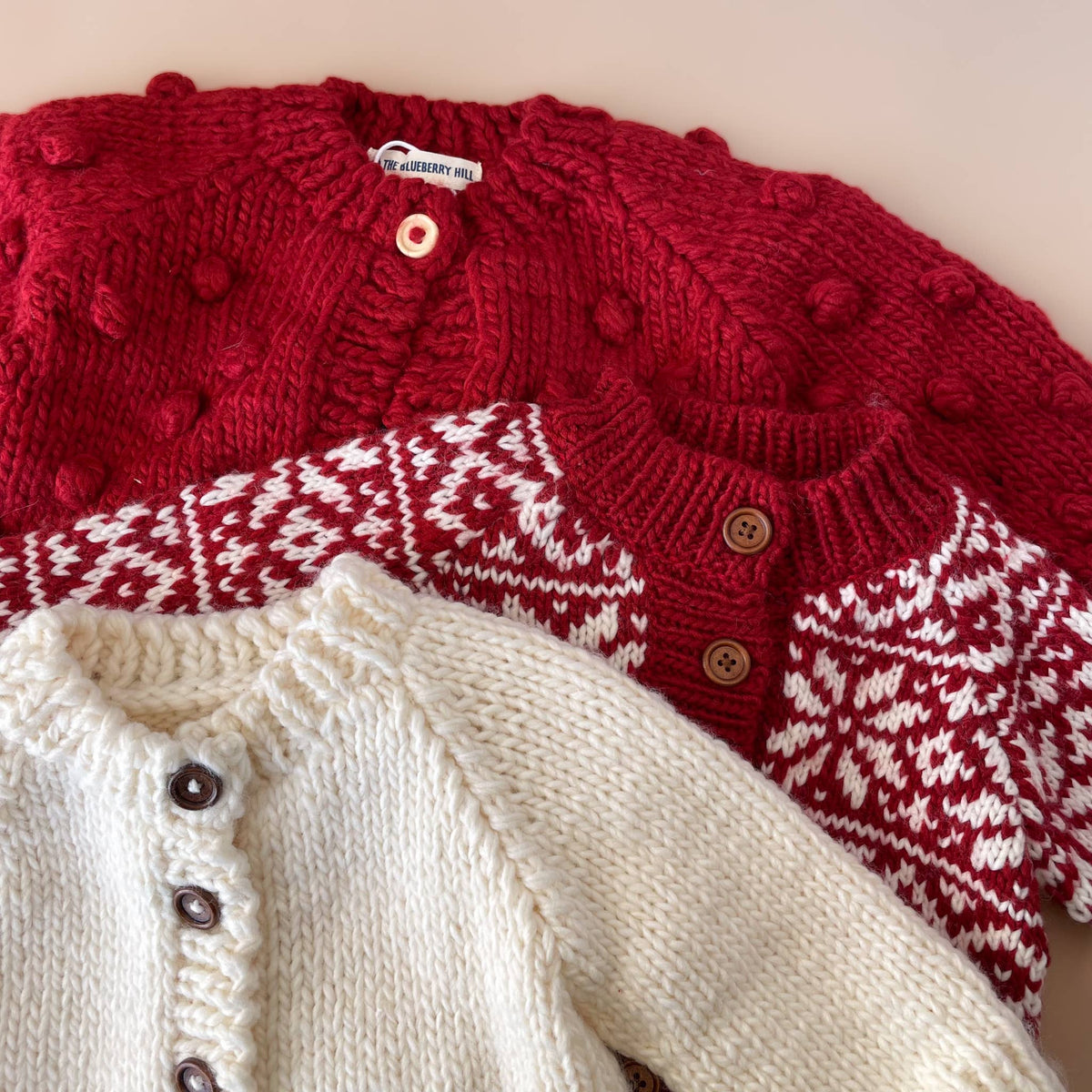 The Blueberry Hill Close-up of red Popcorn Cardigan layered with cream knitwear