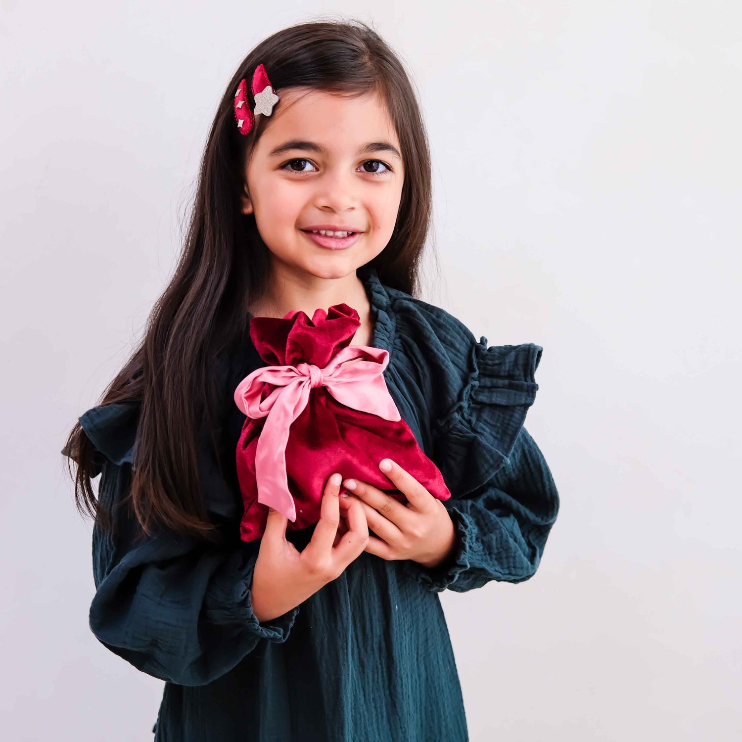 Child holding Mimi &amp; Lula burgundy gifting pouch