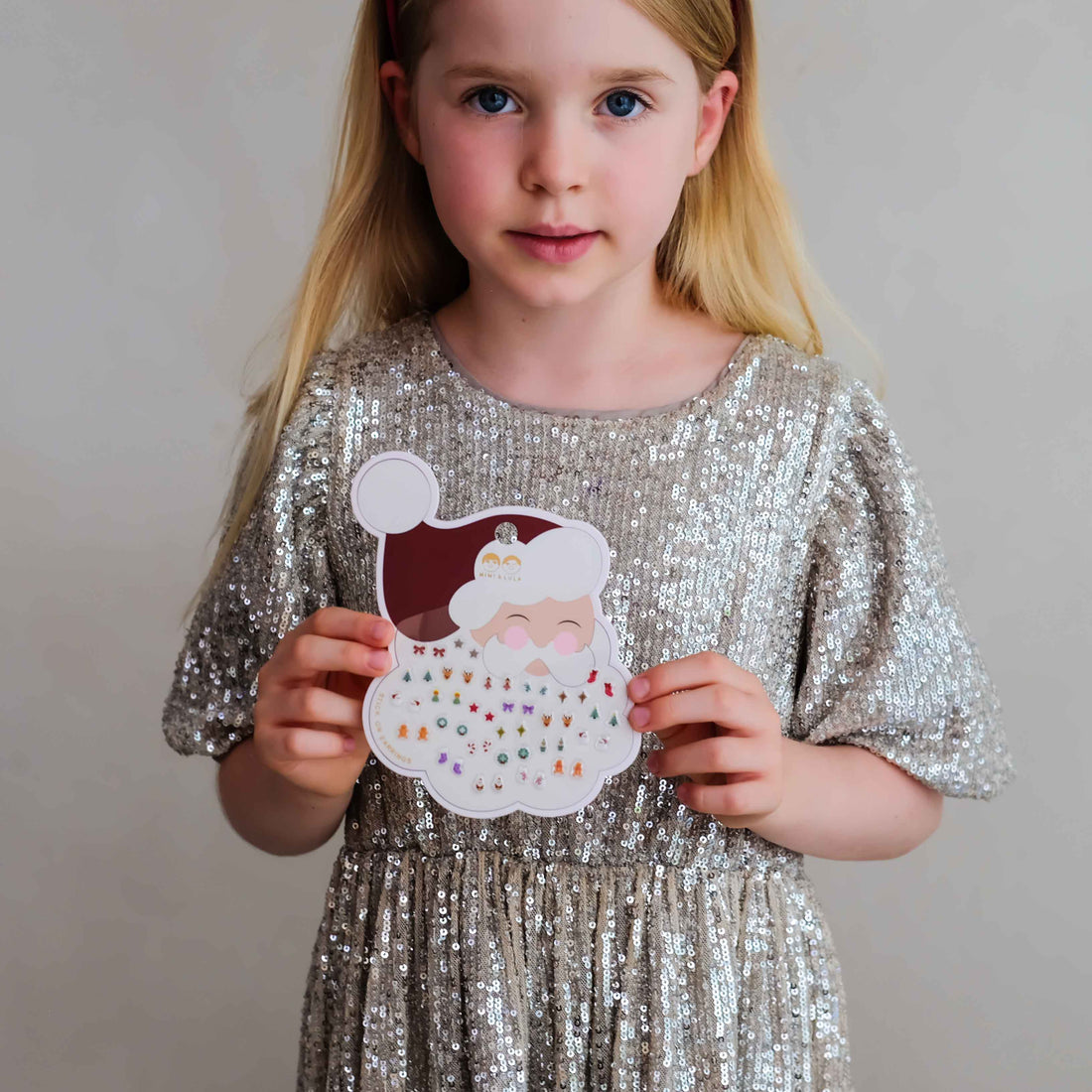 Child holding Mimi &amp; Lula Santa stick-on earrings