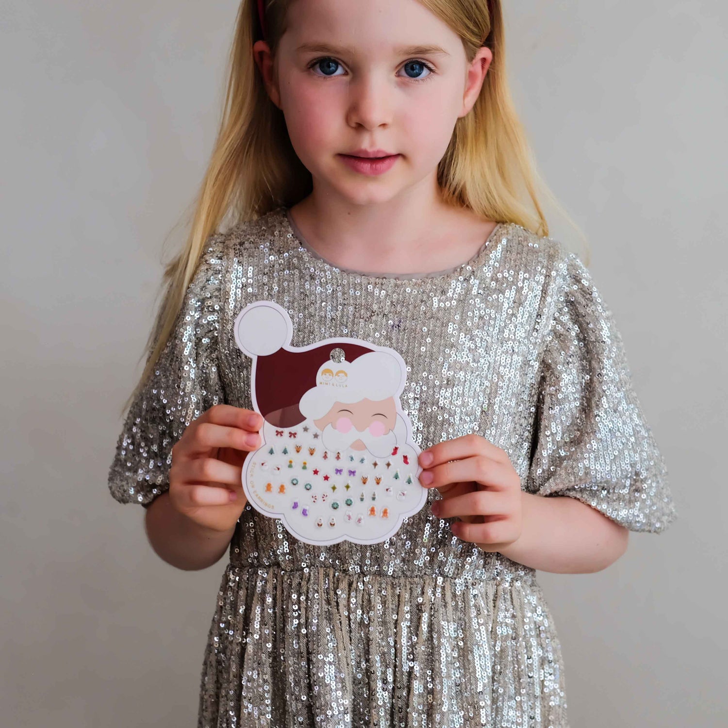Child holding Mimi &amp; Lula Santa stick-on earrings