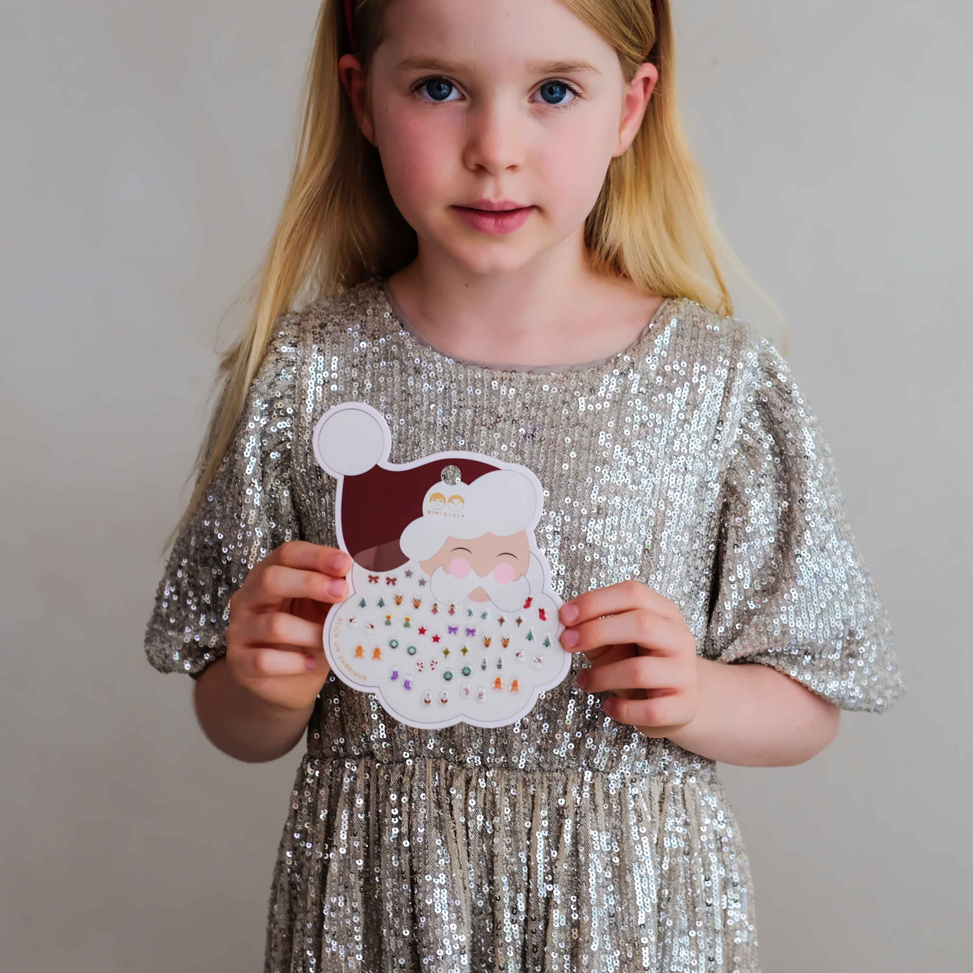 Child holding Mimi &amp; Lula Santa stick-on earrings