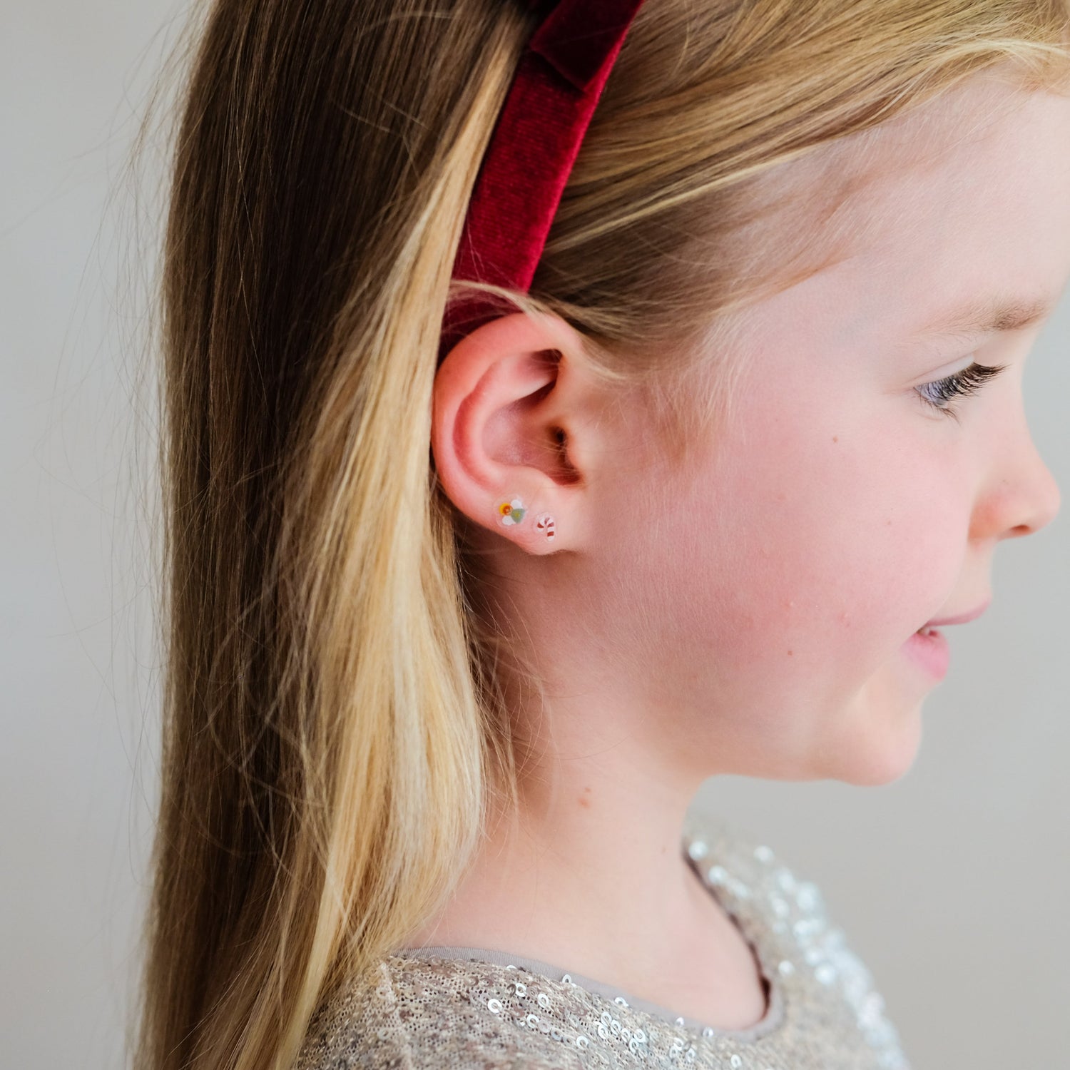 Child wearing Mimi &amp; Lula Santa stick-on earrings