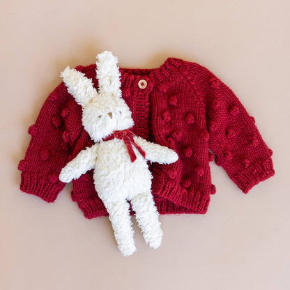 The Blueberry Hill Red Popcorn Cardigan styled with a white bunny plush toy