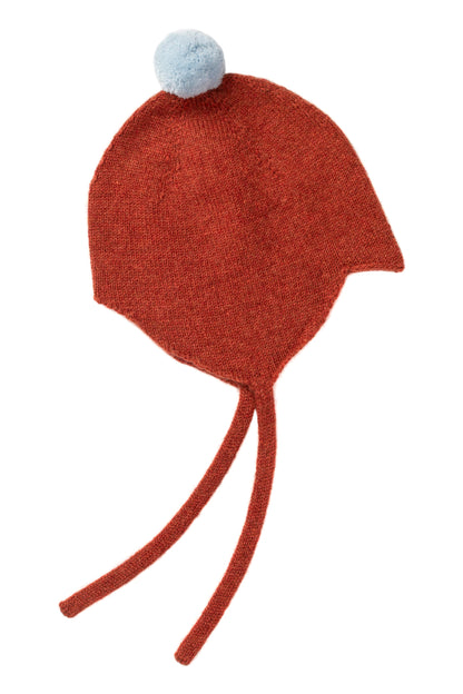 Rosie Sugden cashmere baby bonnet in Rust with Spa Blue pom