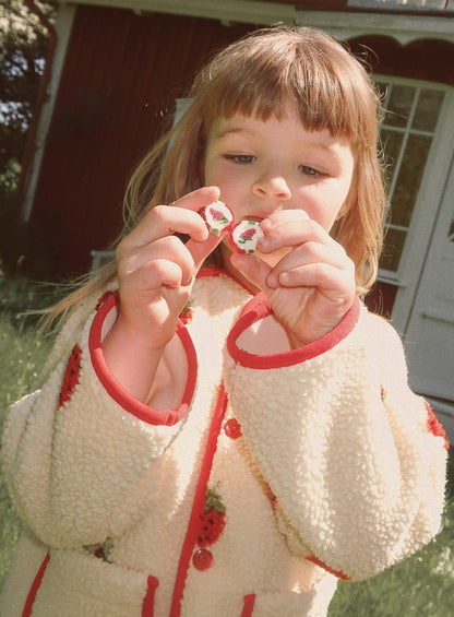 Flöss Strawberry Fleece Jacket in Soft White Berry worn outdoors, front detail