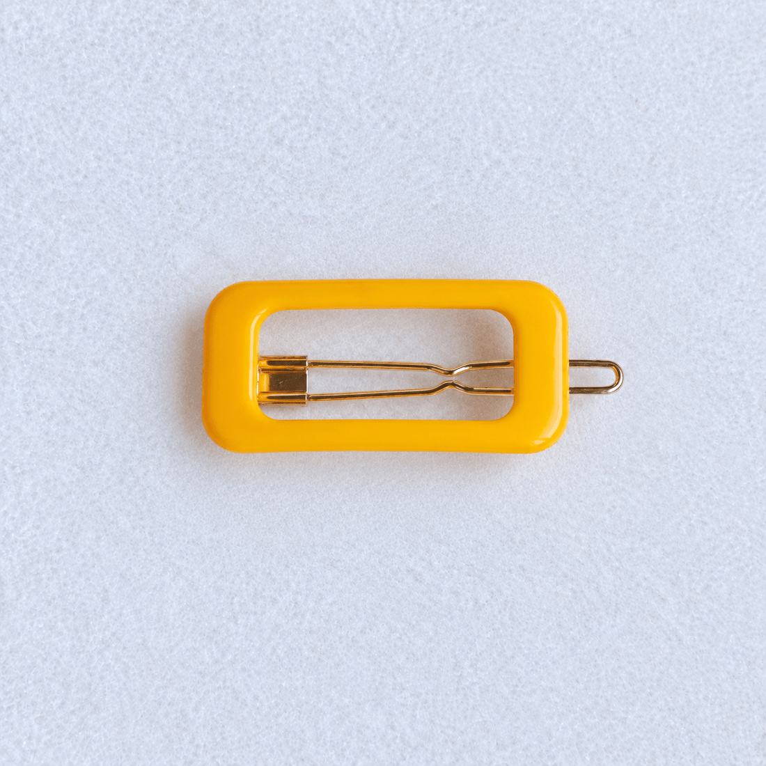 Kanel REC Hair Clip - organge on a pale white textured fabric background
