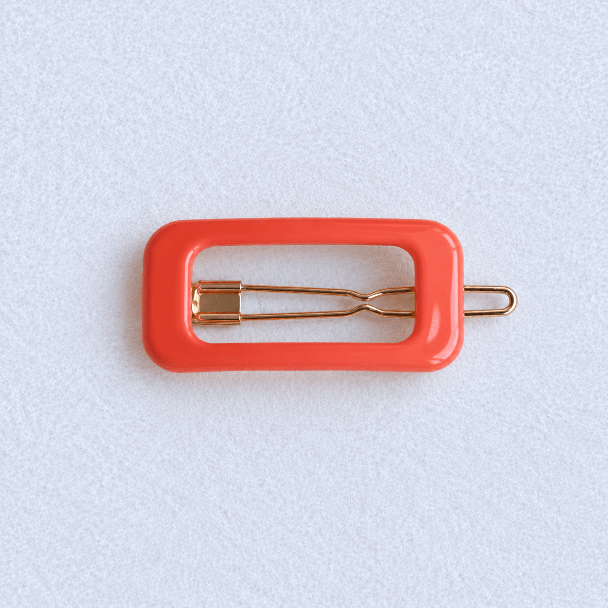 Kanel Rectangle Hair Clip – Orange on a pale white textured fabric background