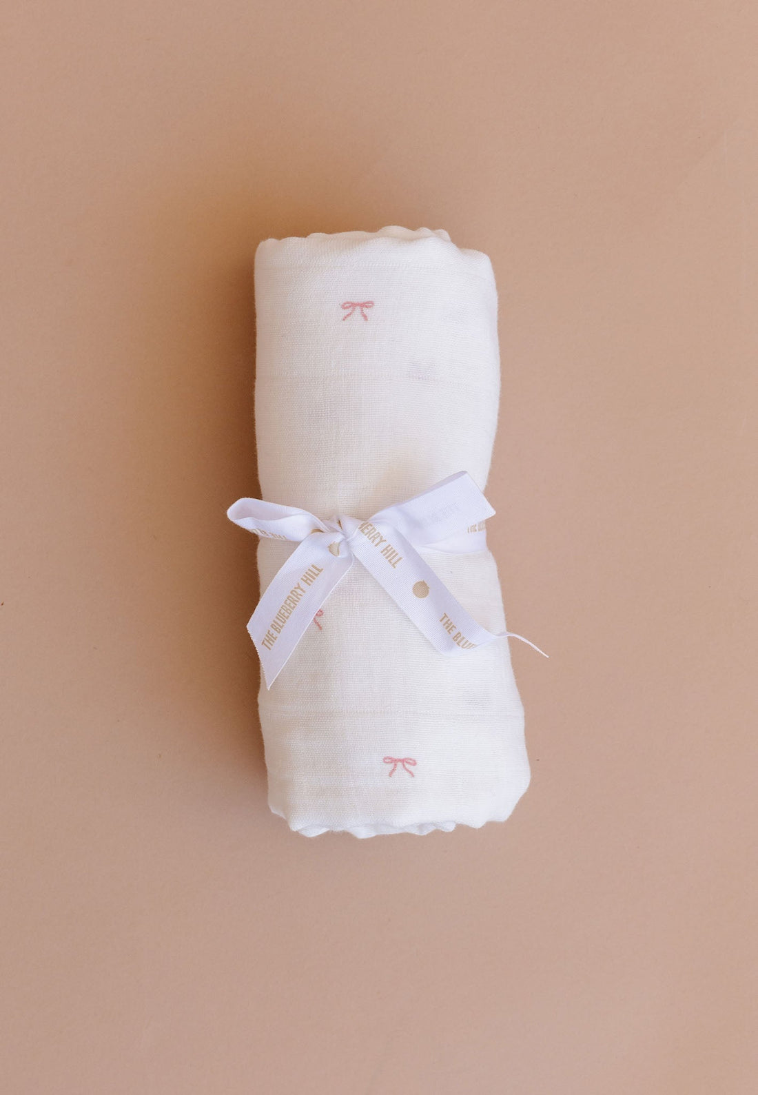 Rolled-up white fabric with a ribbon on a beige background