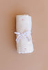 Rolled-up white fabric with a ribbon on a beige background