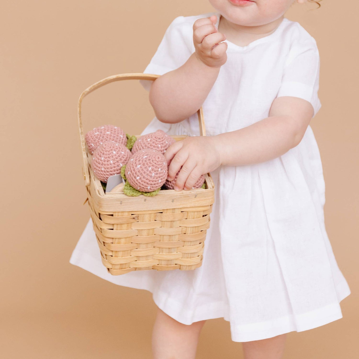 Child holding basket with The Blueberry Hill strawberry crochet teethers
