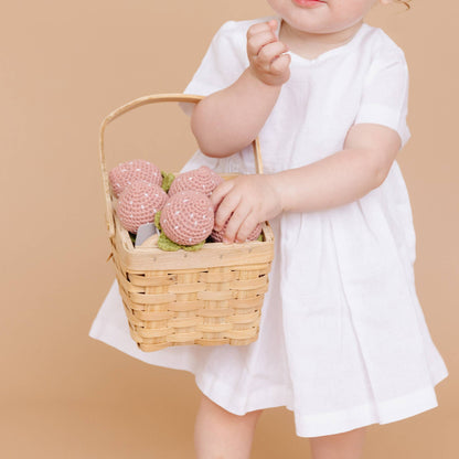 Child holding basket with The Blueberry Hill strawberry crochet teethers
